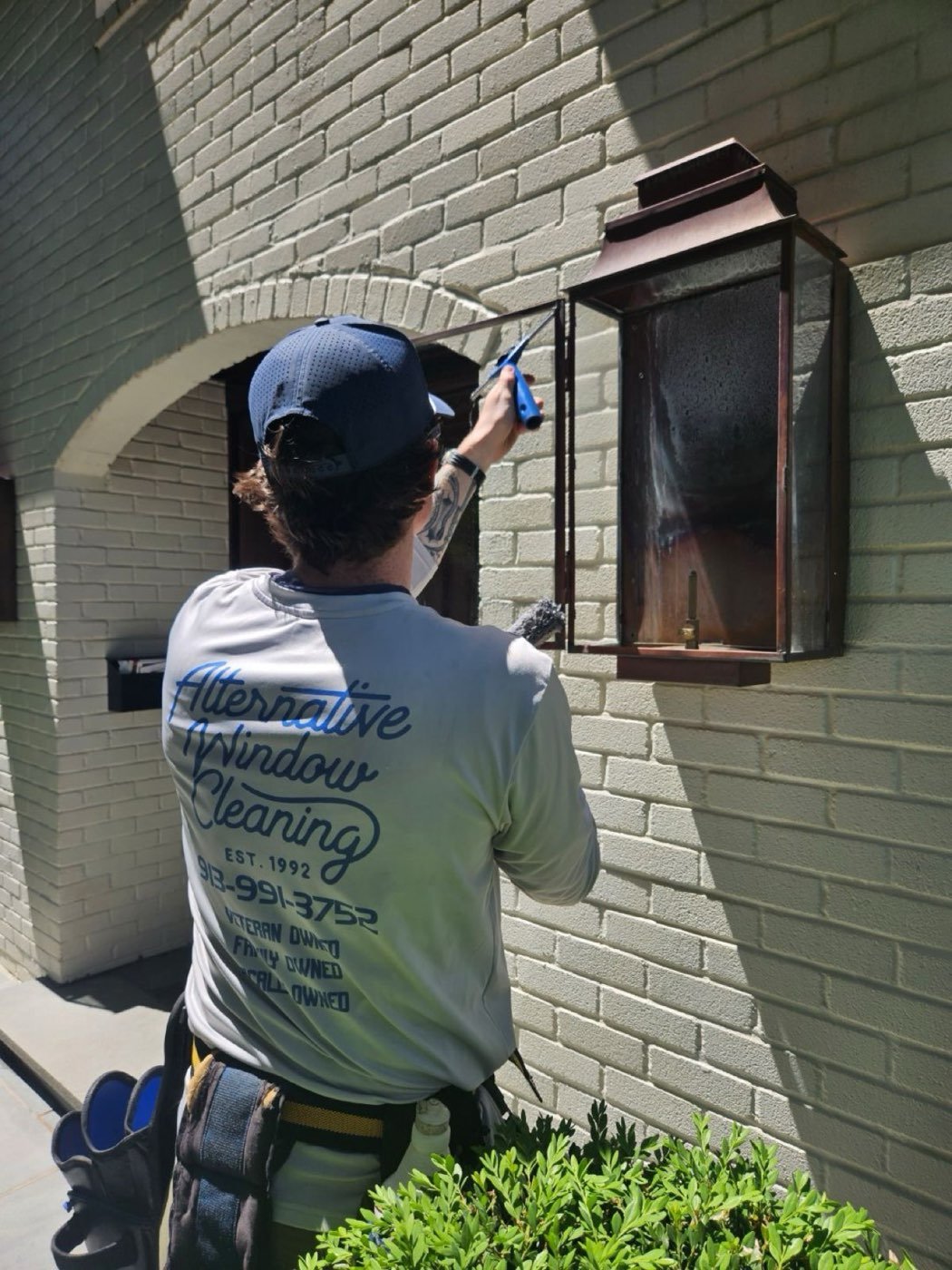 Alternative Window Cleaning technician detailing glass on a Johnson County home